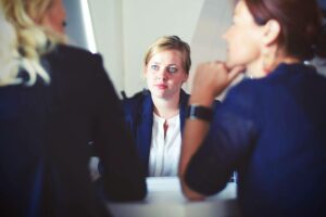 Woman in an interview being interviewed by two women. Asking do you love your job?